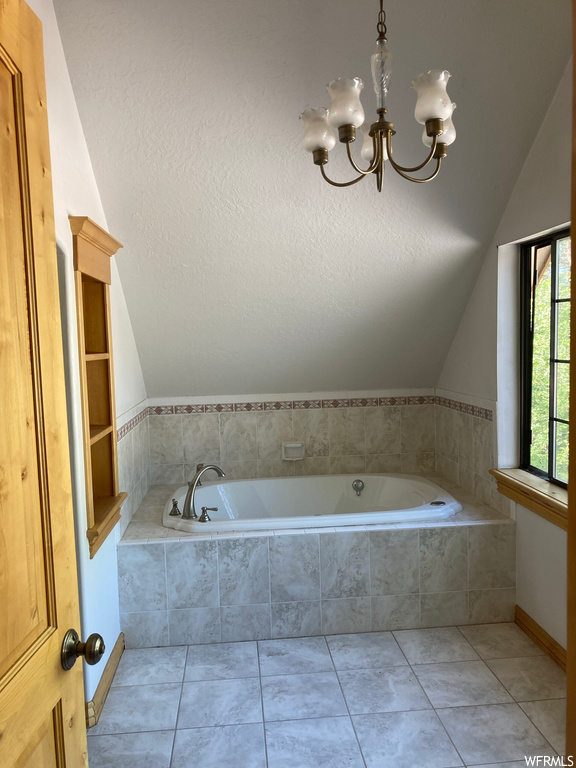 Bathroom featuring lofted ceiling, tile floors, tiled tub, and a chandelier