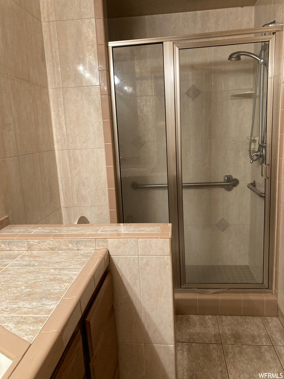 Bathroom with an enclosed shower, tile walls, and tile flooring
