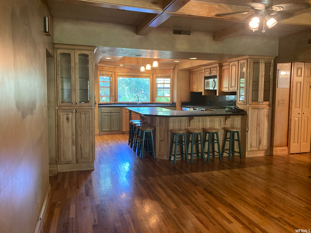 Kitchen featuring ceiling fan, dark hardwood / wood-style flooring, a kitchen island, and a kitchen breakfast bar
