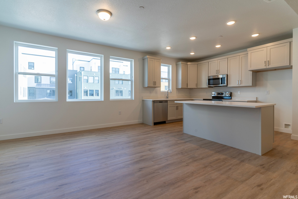 Kitchen with sink, a center island, stainless steel appliances, and light hardwood / wood-style floors