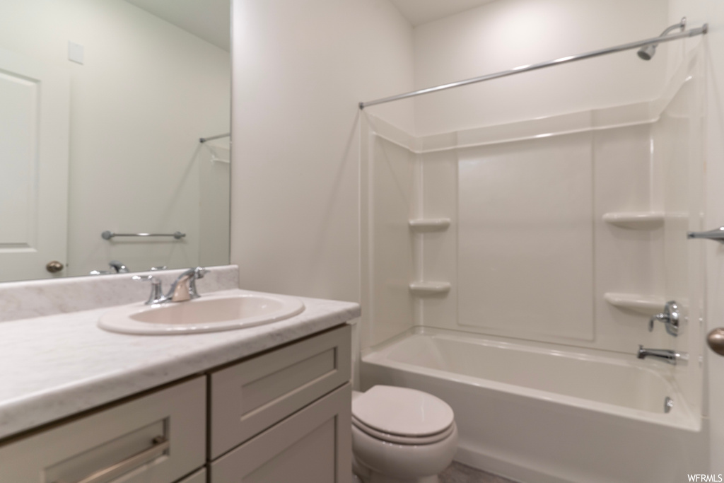 Full bathroom featuring toilet, washtub / shower combination, and vanity with extensive cabinet space