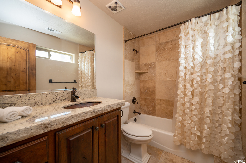 Full bathroom featuring toilet, a textured ceiling, tile flooring, shower / tub combo with curtain, and large vanity