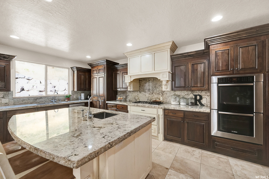 Kitchen with sink, a breakfast bar area, stainless steel appliances, backsplash, and light tile floors