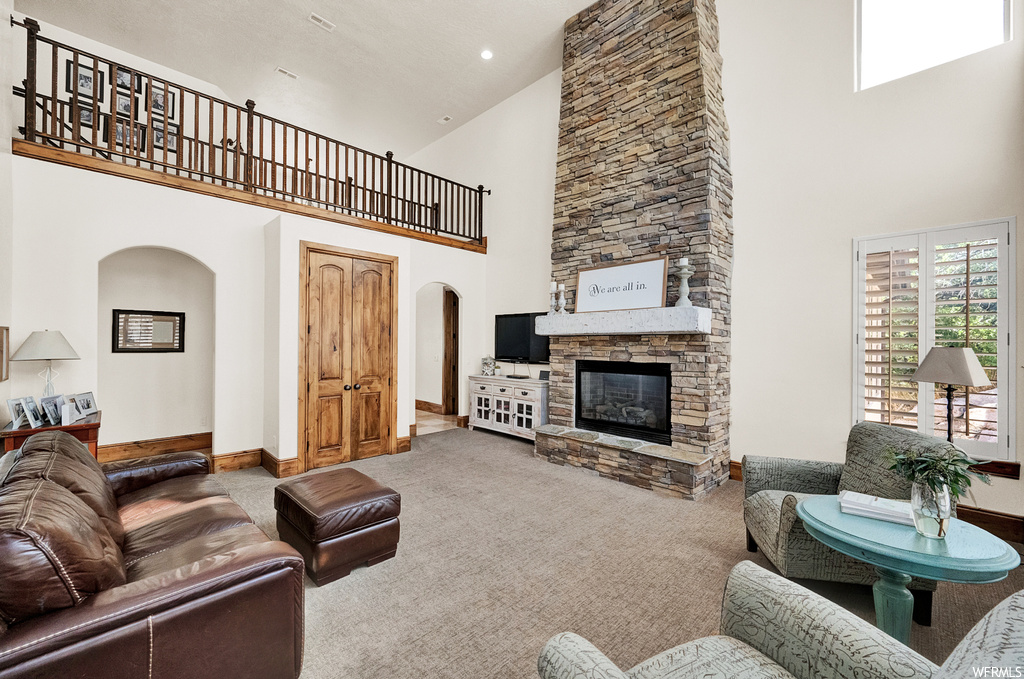 Carpeted living room featuring a fireplace and high vaulted ceiling