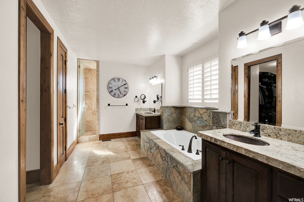 Bathroom with shower with separate bathtub, tile floors, double sink vanity, and a textured ceiling