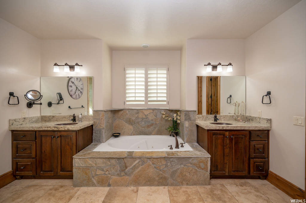 Bathroom featuring dual sinks, a relaxing tiled bath, and large vanity
