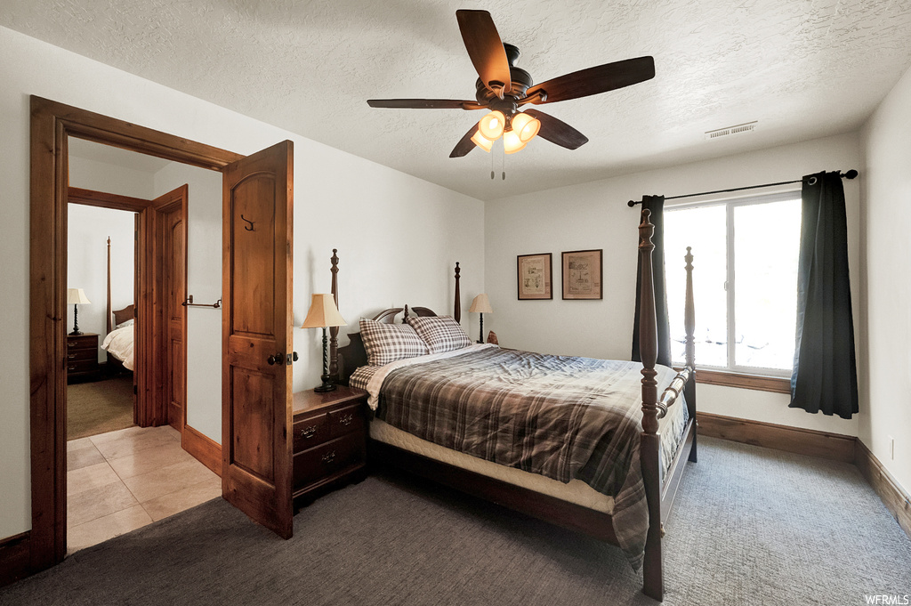 Bedroom featuring ceiling fan, a textured ceiling, and light tile floors