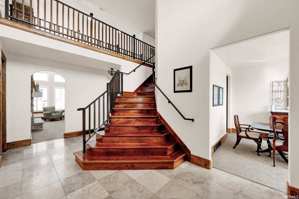 Staircase with a high ceiling and light tile floors