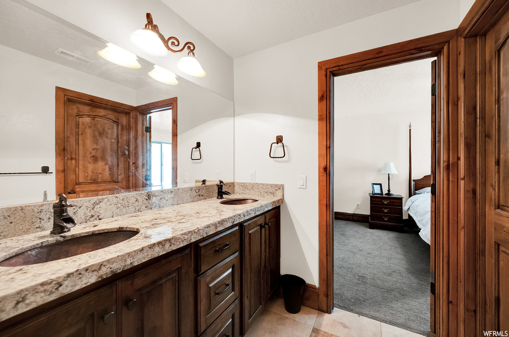 Bathroom with tile flooring, vanity with extensive cabinet space, and dual sinks