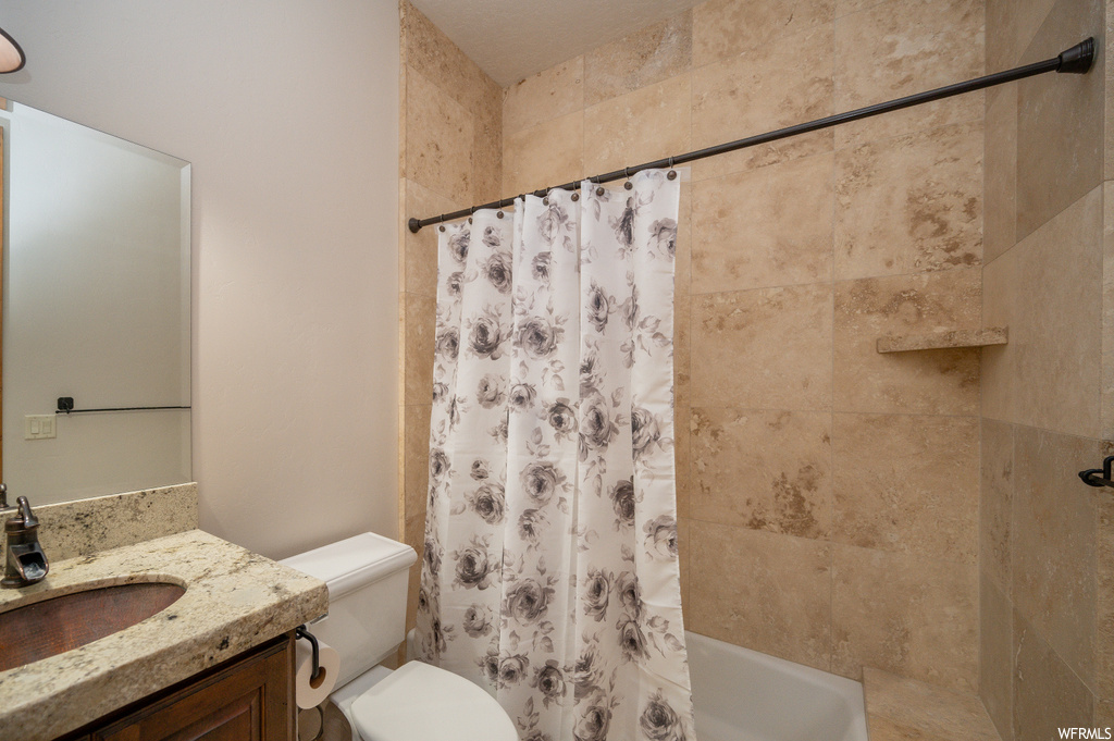 Full bathroom featuring shower / bath combo with shower curtain, vanity, and toilet