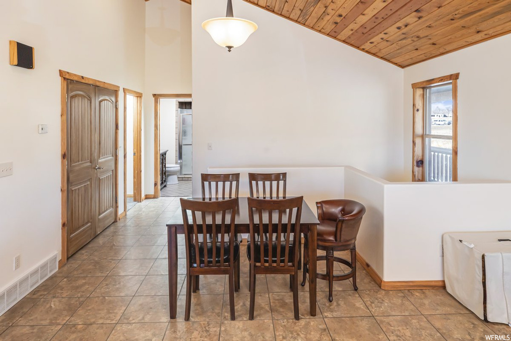 Dining area with high vaulted ceiling, wooden ceiling, and light tile floors