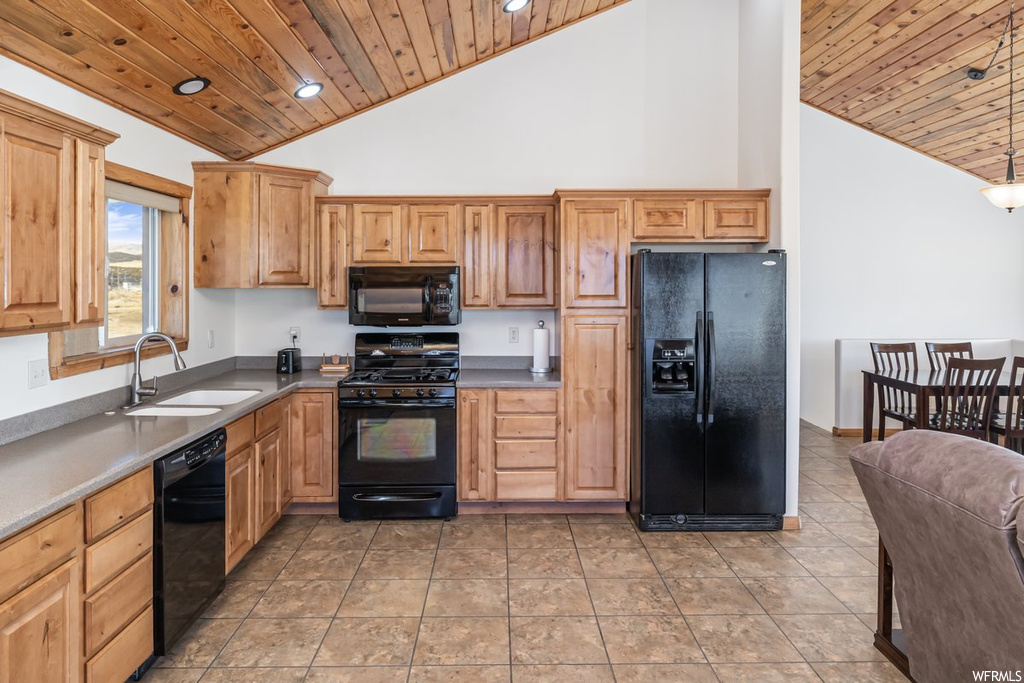 Kitchen featuring black appliances, light tile floors, sink, and high vaulted ceiling