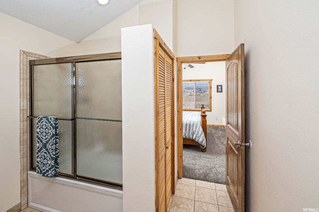 Bathroom featuring tile floors, enclosed tub / shower combo, and vaulted ceiling