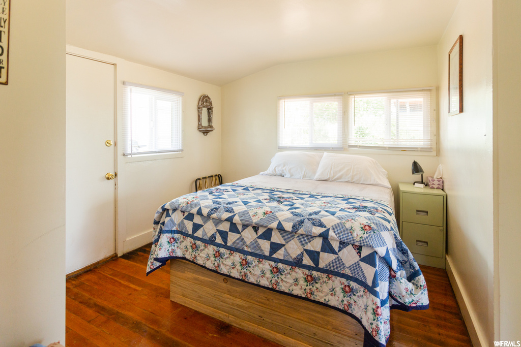 Bedroom with lofted ceiling, dark hardwood / wood-style flooring, and multiple windows