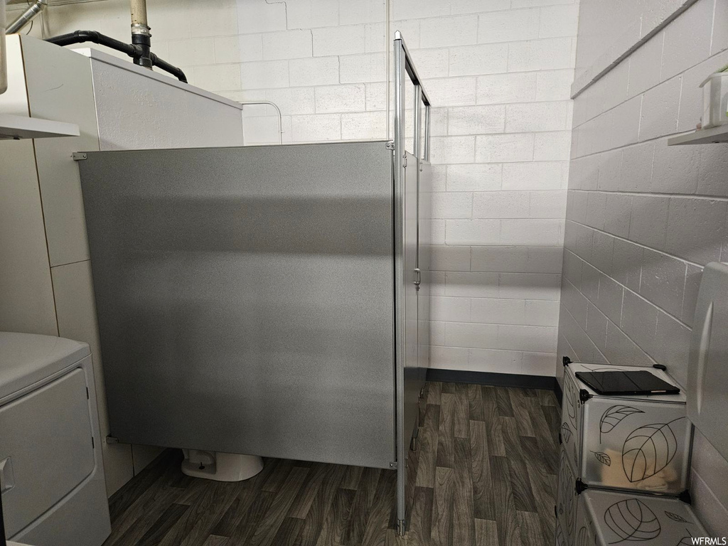 Bathroom featuring toilet, washer and clothes dryer, and wood-type flooring