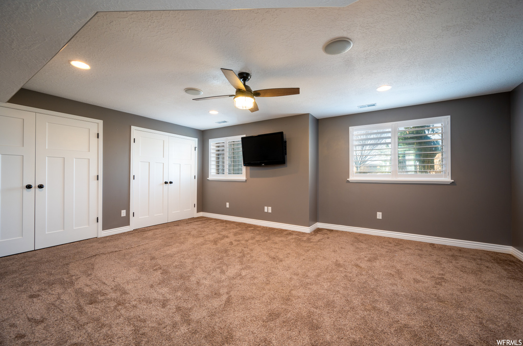 Spare room with ceiling fan, a textured ceiling, and light carpet