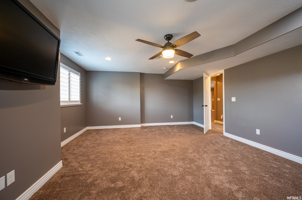 Unfurnished room featuring ceiling fan, a textured ceiling, light colored carpet, and vaulted ceiling