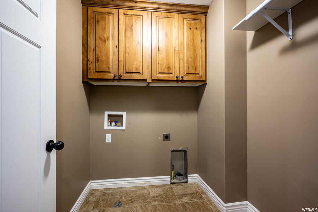 Laundry room with hookup for an electric dryer, cabinets, tile flooring, and hookup for a washing machine