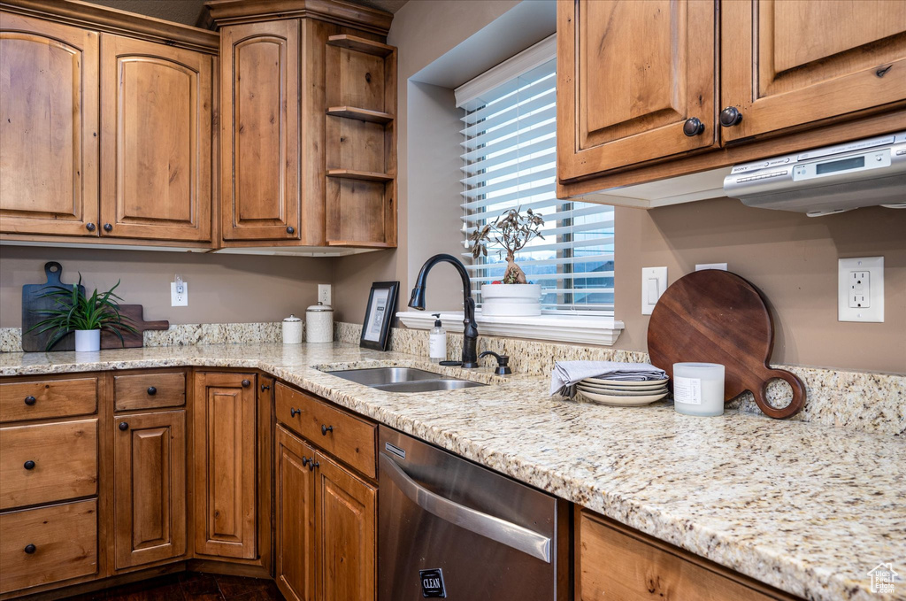 Kitchen featuring sink, dishwasher, and light stone countertops