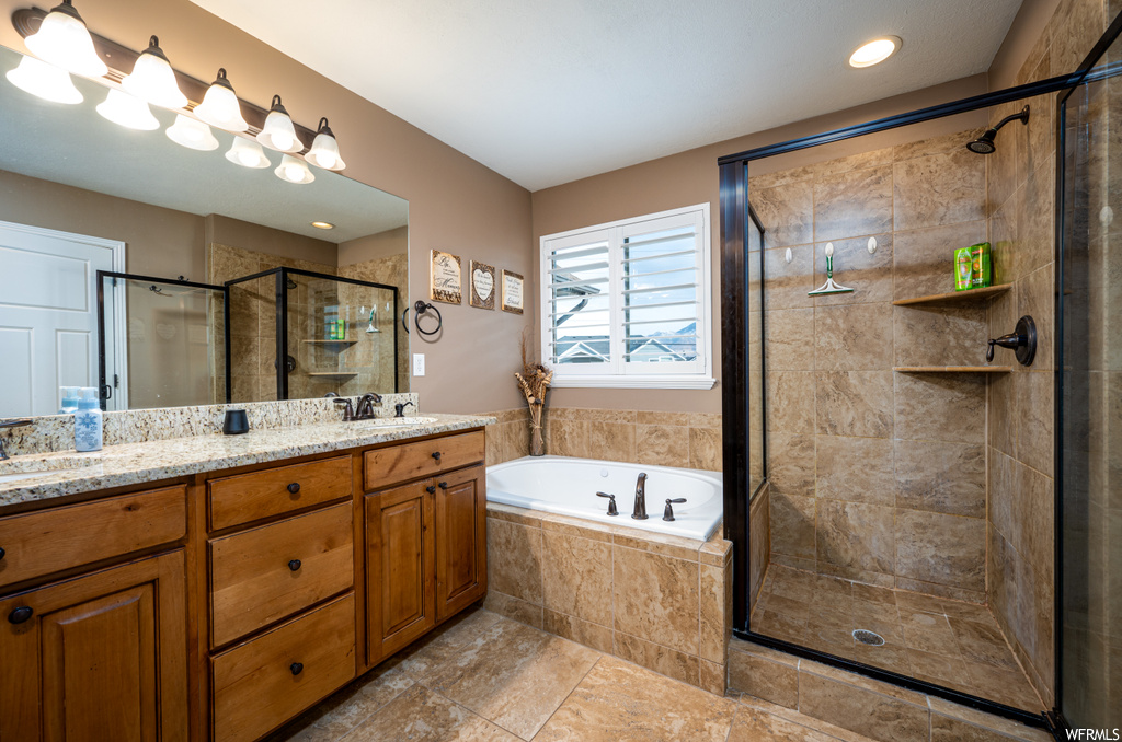 Bathroom featuring separate shower and tub, double sink vanity, and tile flooring