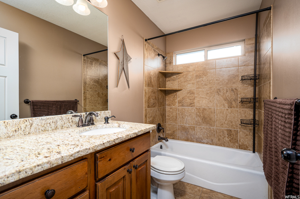 Full bathroom featuring tiled shower / bath, vanity, toilet, and tile floors