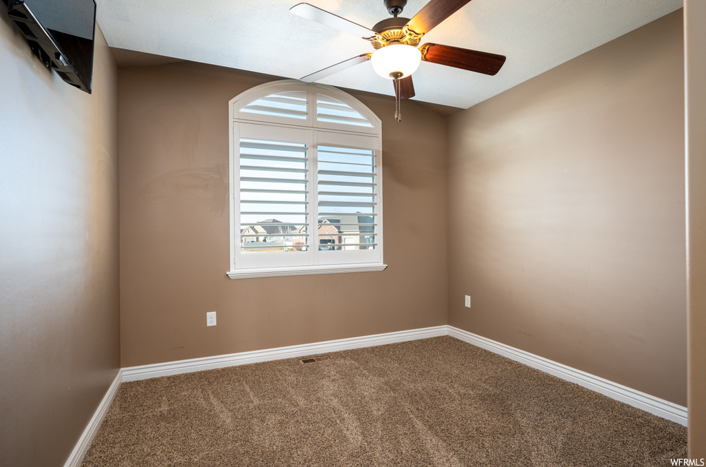 Spare room featuring ceiling fan and carpet