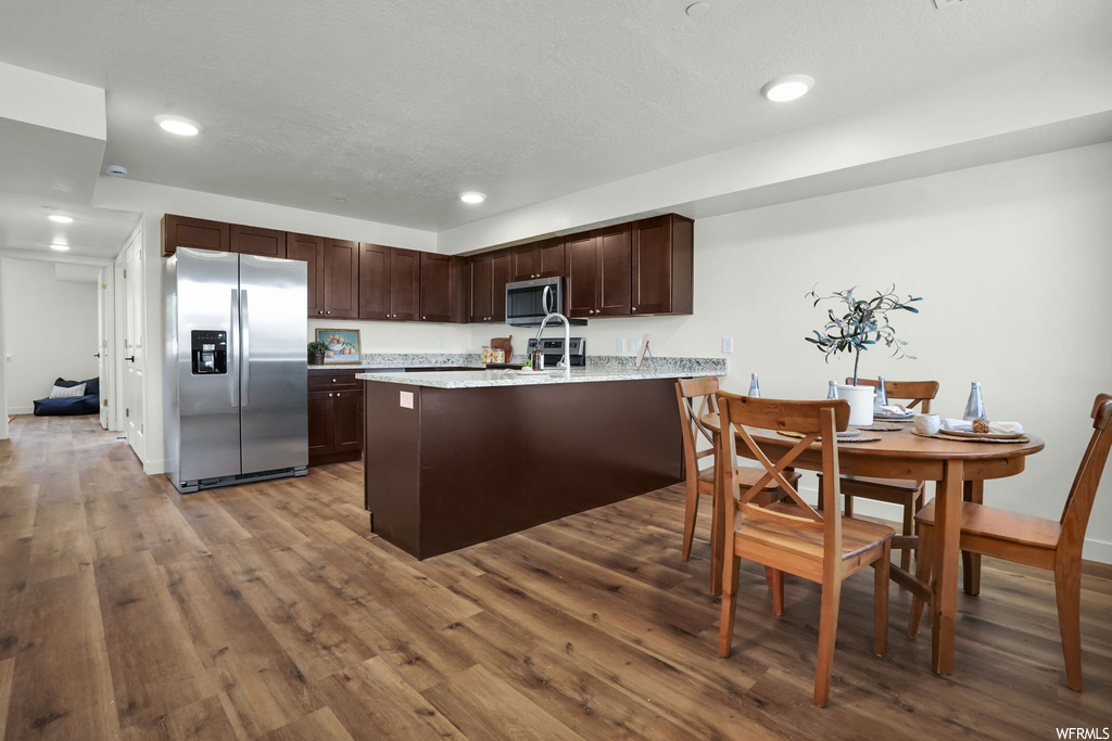 Kitchen with dark hardwood / wood-style flooring, dark brown cabinetry, and stainless steel appliances