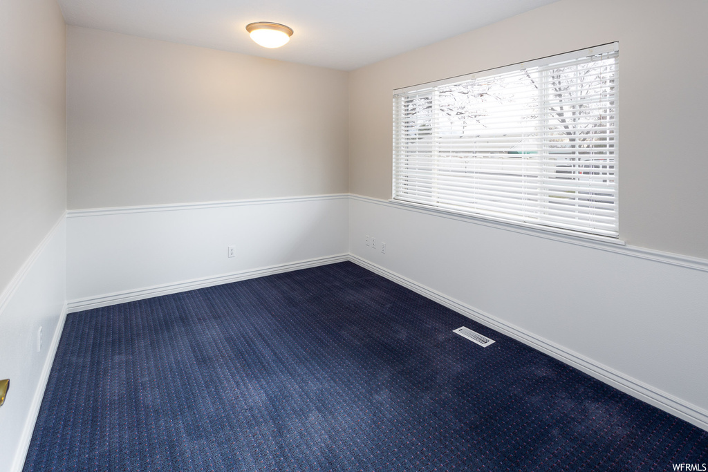 Unfurnished room with dark carpet and a healthy amount of sunlight