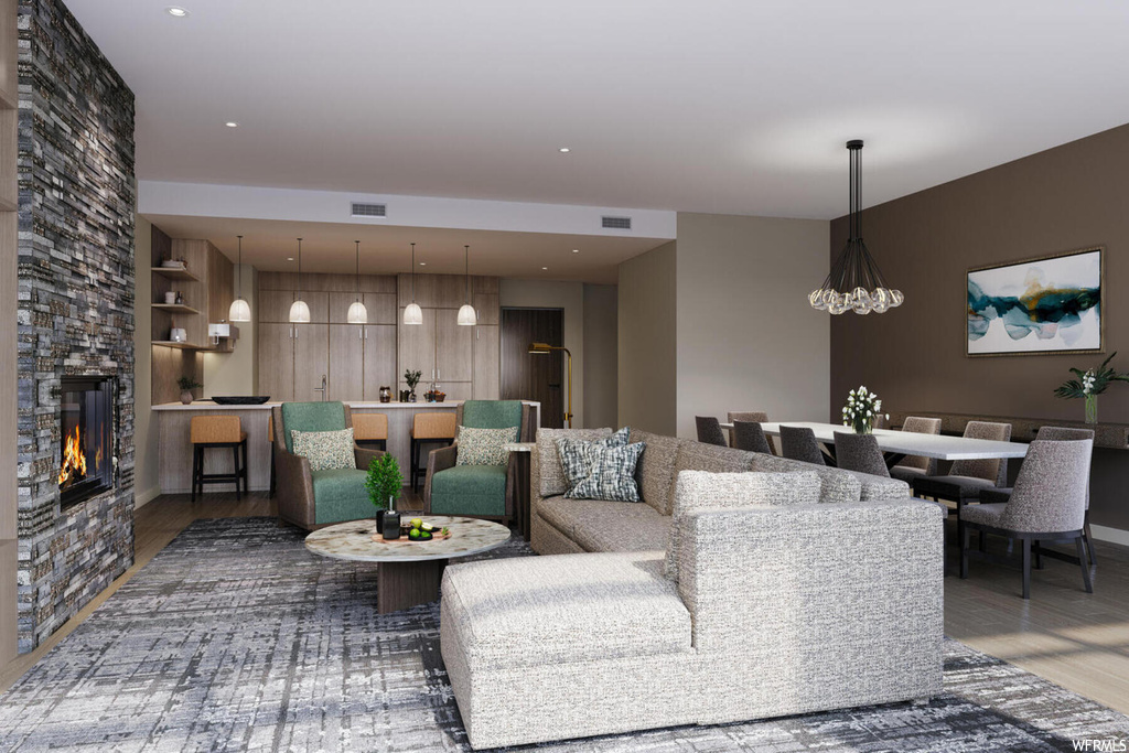 Living room featuring dark hardwood / wood-style flooring, an inviting chandelier, and a stone fireplace