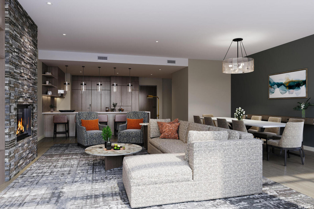 Living room featuring dark hardwood / wood-style floors, an inviting chandelier, and a stone fireplace