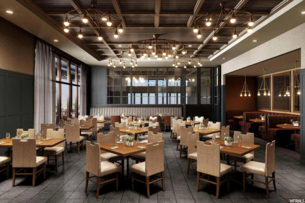 Dining space featuring dark tile flooring, a high ceiling, and a notable chandelier