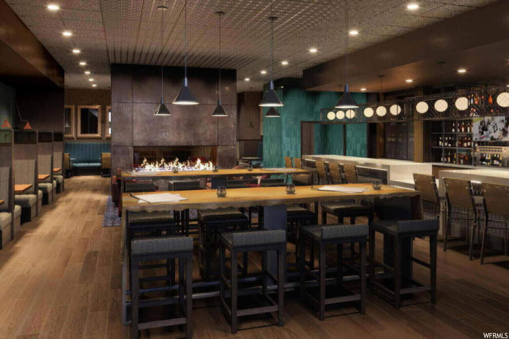 Bar featuring dark brown cabinets, hanging light fixtures, and light hardwood / wood-style flooring