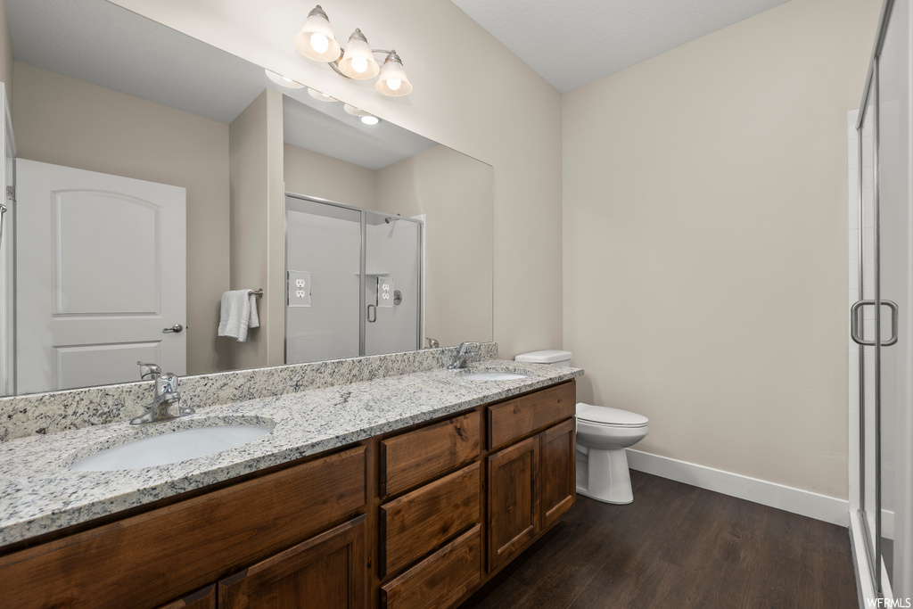 Bathroom featuring toilet, oversized vanity, walk in shower, double sink, and hardwood / wood-style floors