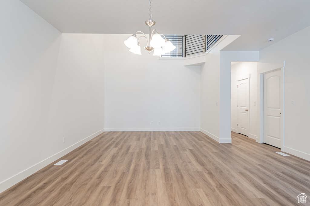 Unfurnished room with an inviting chandelier and light wood-type flooring