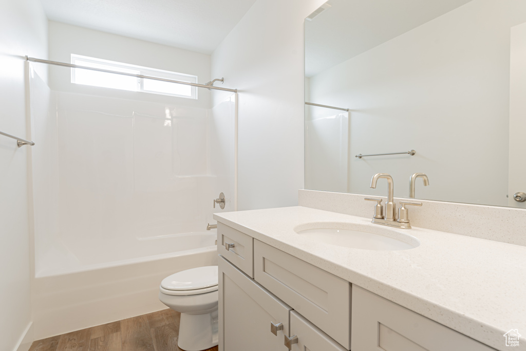 Full bathroom with toilet, wood-type flooring, washtub / shower combination, and vanity