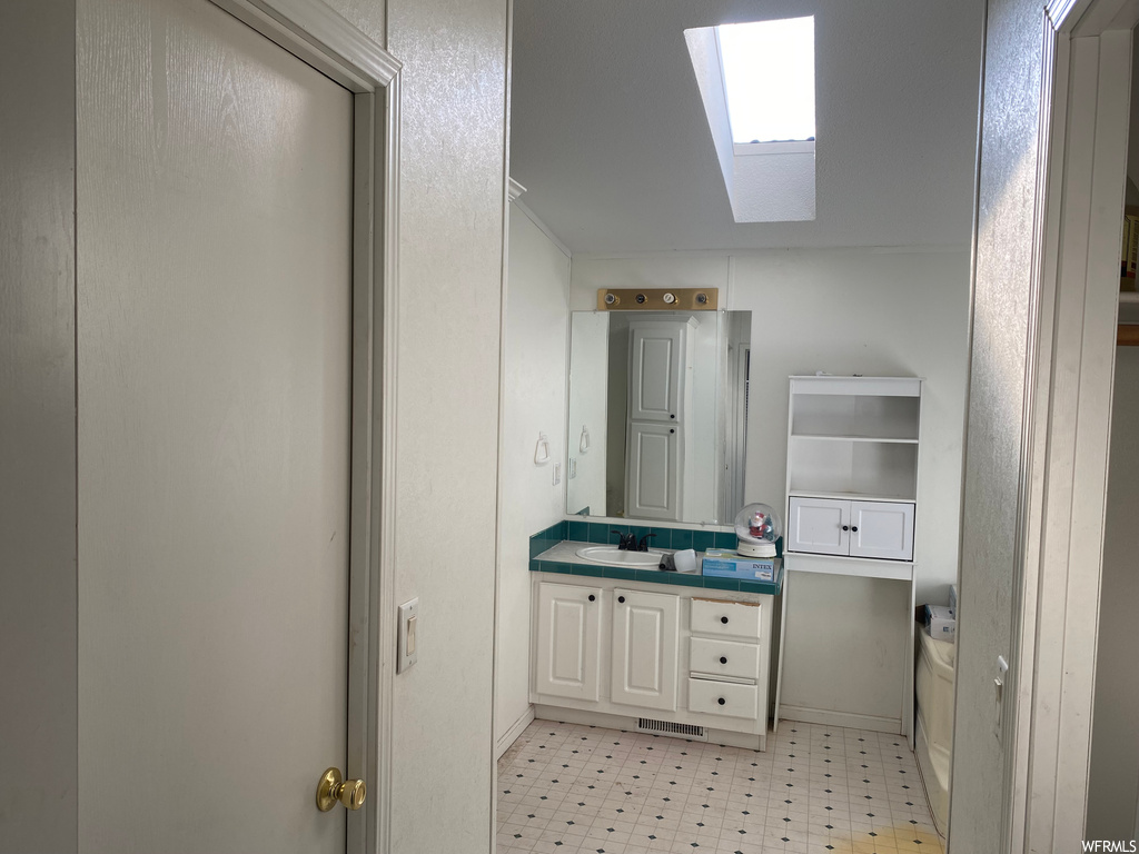 Bathroom with vanity, tile floors, and a skylight