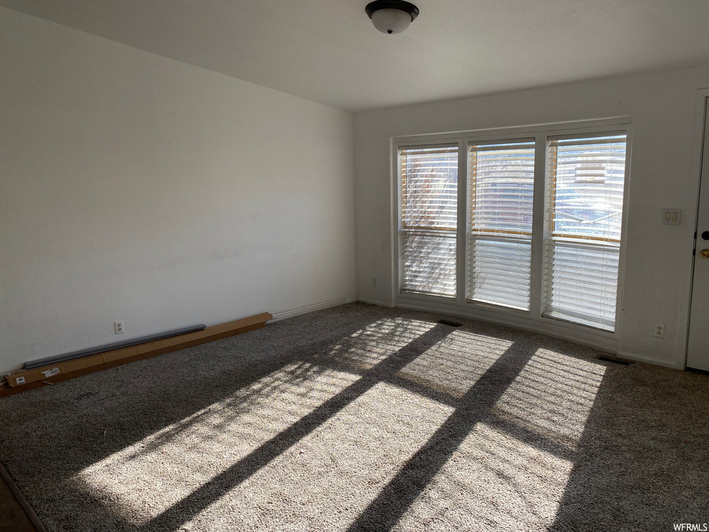 Spare room with a wealth of natural light and dark colored carpet