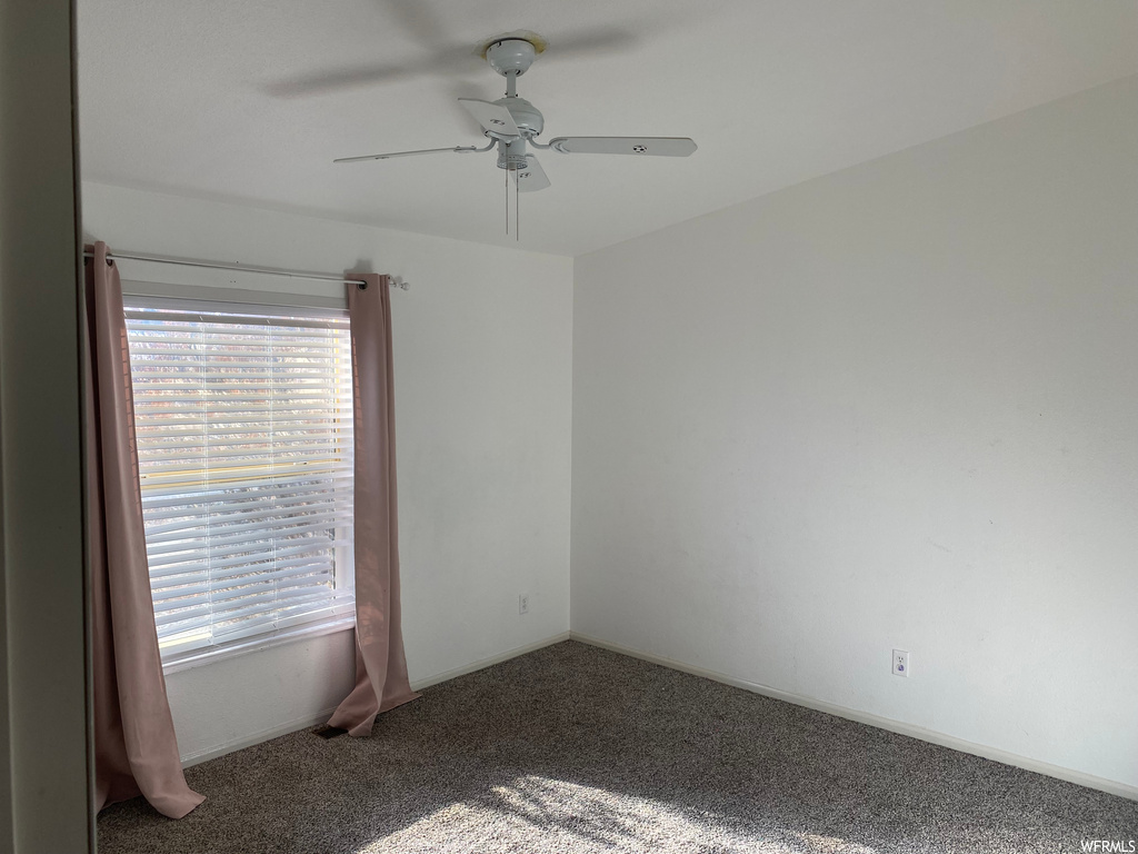 Carpeted empty room featuring ceiling fan