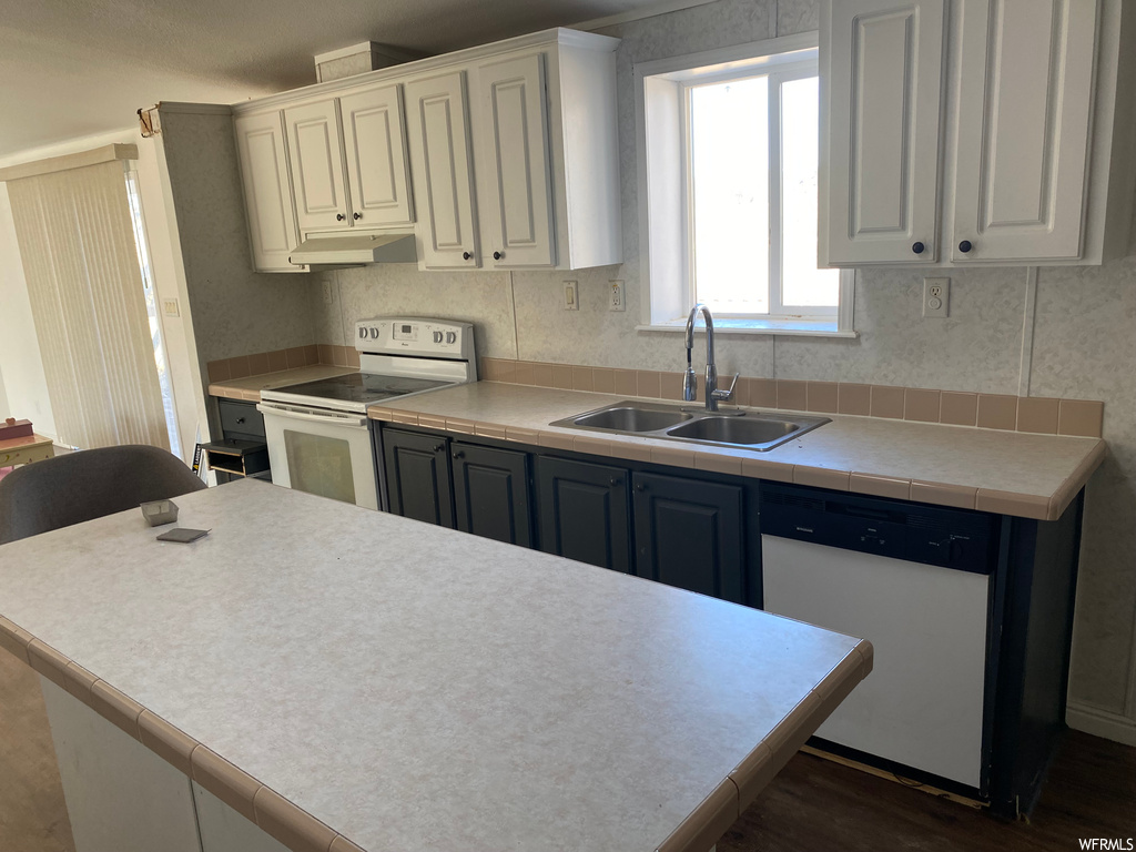 Kitchen with dark hardwood / wood-style floors, sink, white appliances, and white cabinetry