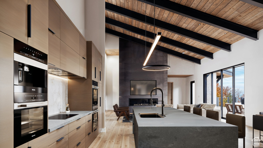 Kitchen featuring wooden ceiling, light stone counters, high vaulted ceiling, sink, and light hardwood / wood-style flooring