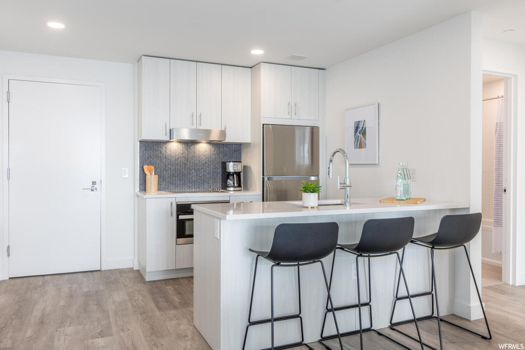 Kitchen featuring a kitchen breakfast bar, light hardwood / wood-style floors, and stainless steel appliances