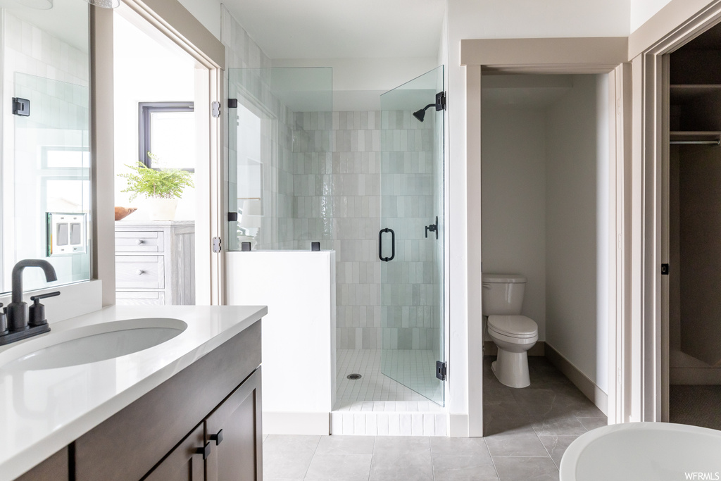 Bathroom with vanity, toilet, a shower with shower door, and tile flooring