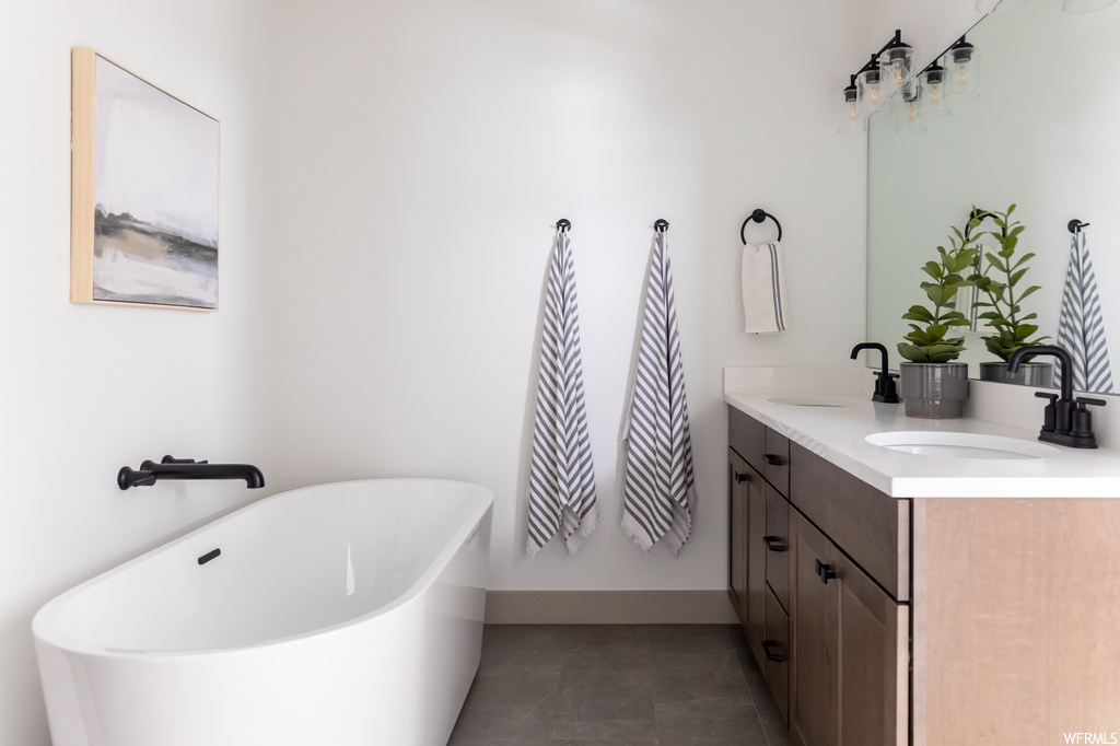 Bathroom featuring a bathing tub, double sink, tile floors, and large vanity