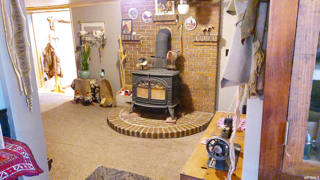 Living room with a wood stove, carpet flooring, and brick wall