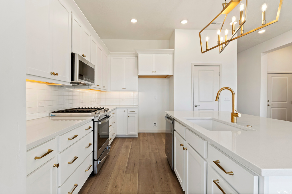 Kitchen featuring sink, light hardwood / wood-style floors, a kitchen island with sink, stainless steel appliances, and white cabinetry