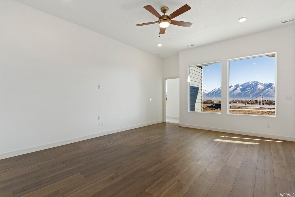 Empty room with dark hardwood / wood-style floors, ceiling fan, and a mountain view