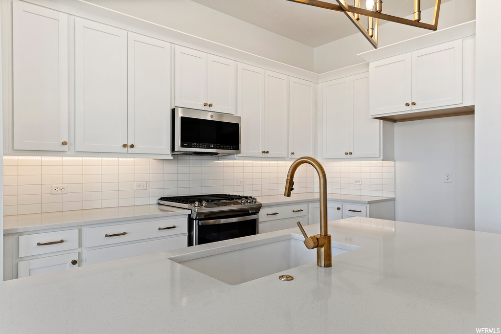 Kitchen featuring white cabinets, sink, stainless steel appliances, and backsplash