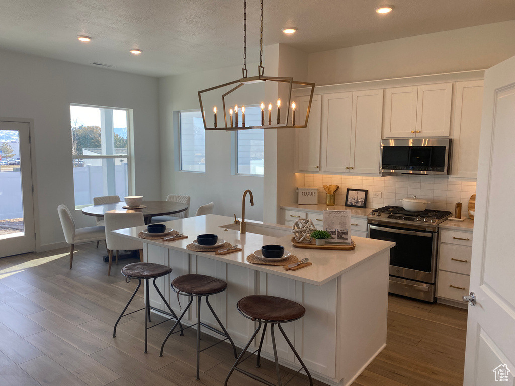 Kitchen featuring hanging light fixtures, white cabinetry, dark hardwood / wood-style flooring, sink, and stainless steel appliances