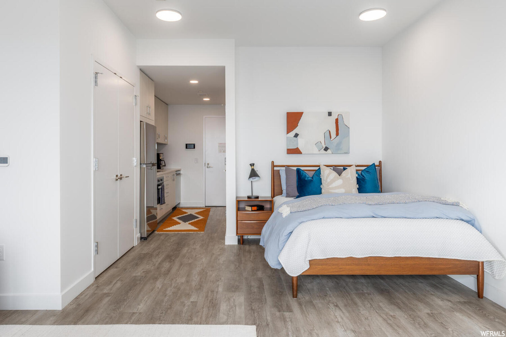 Bedroom with light hardwood / wood-style flooring and stainless steel refrigerator