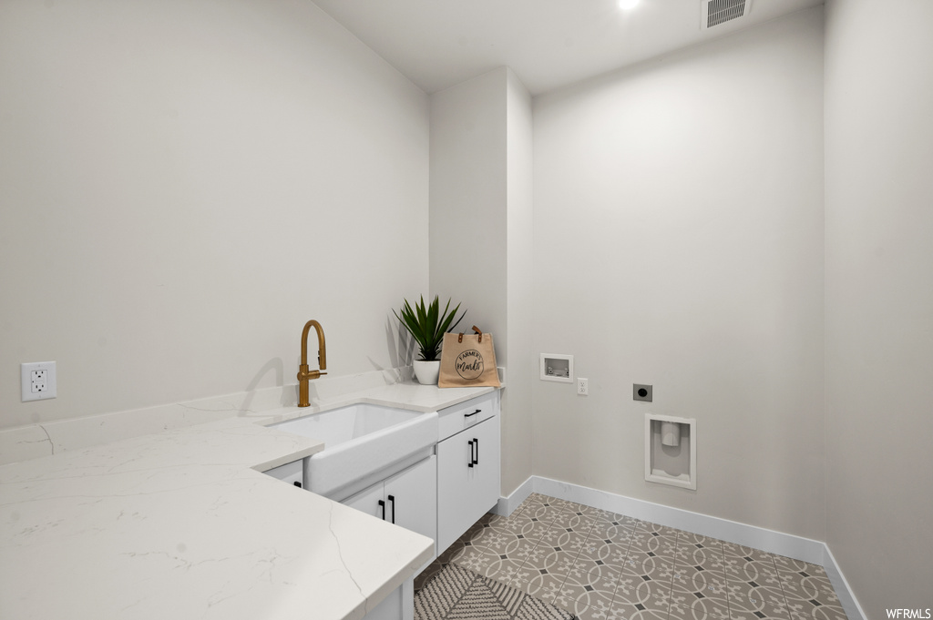 Clothes washing area with light tile floors, sink, cabinets, hookup for an electric dryer, and hookup for a washing machine
